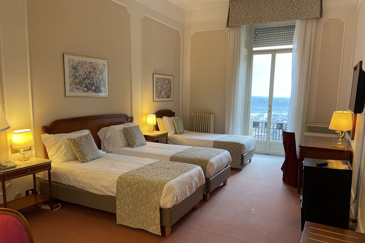 Une chambre d’hôtel avec deux lits, un bureau, une chaise et une vue sur la ville.
