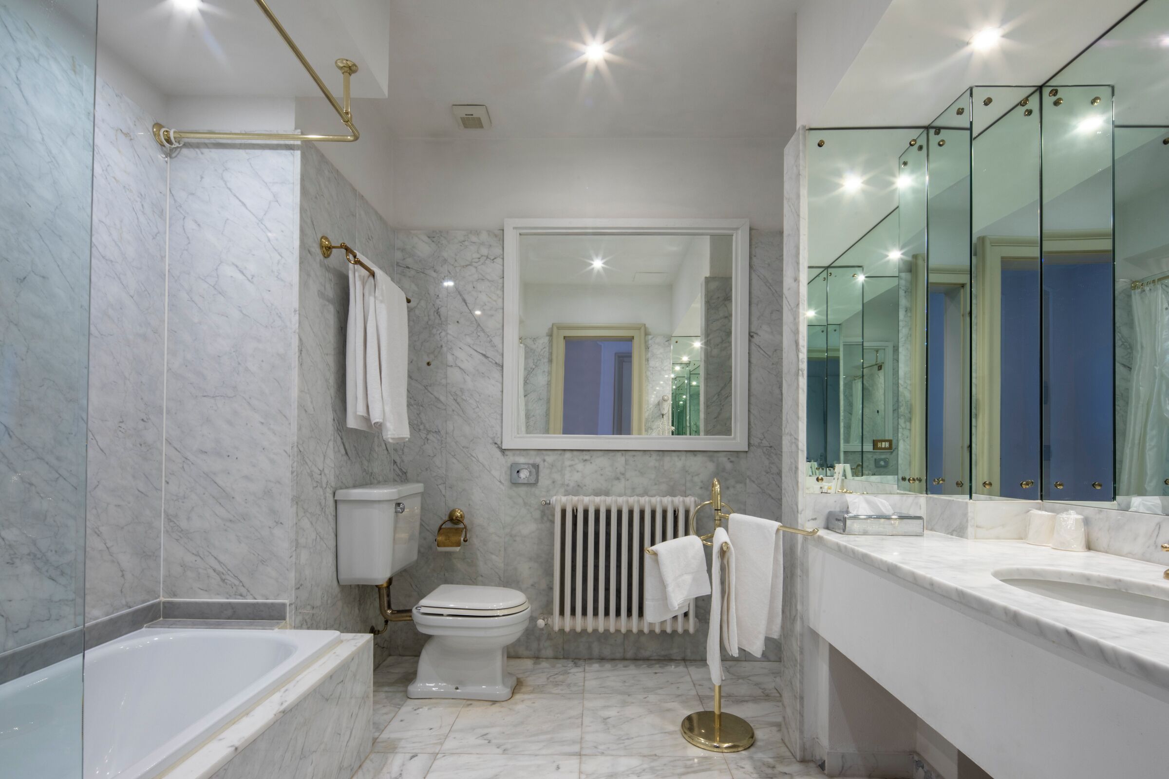 Un baño moderno con bañera, inodoro y tocador con un espejo grande.