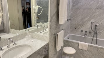 A bathroom with two sinks, a large mirror, a bathtub, and a toilet.