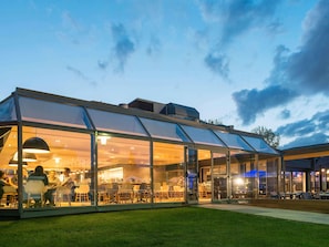 Un edificio moderno con techo de vidrio, terraza al aire libre y paredes de ladrillo.
