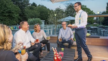 Un groupe de personnes est assis sur une terrasse. Au premier plan, on aperçoit une table, une piscine et, à l’arrière-plan, des sièges d’extérieur.
