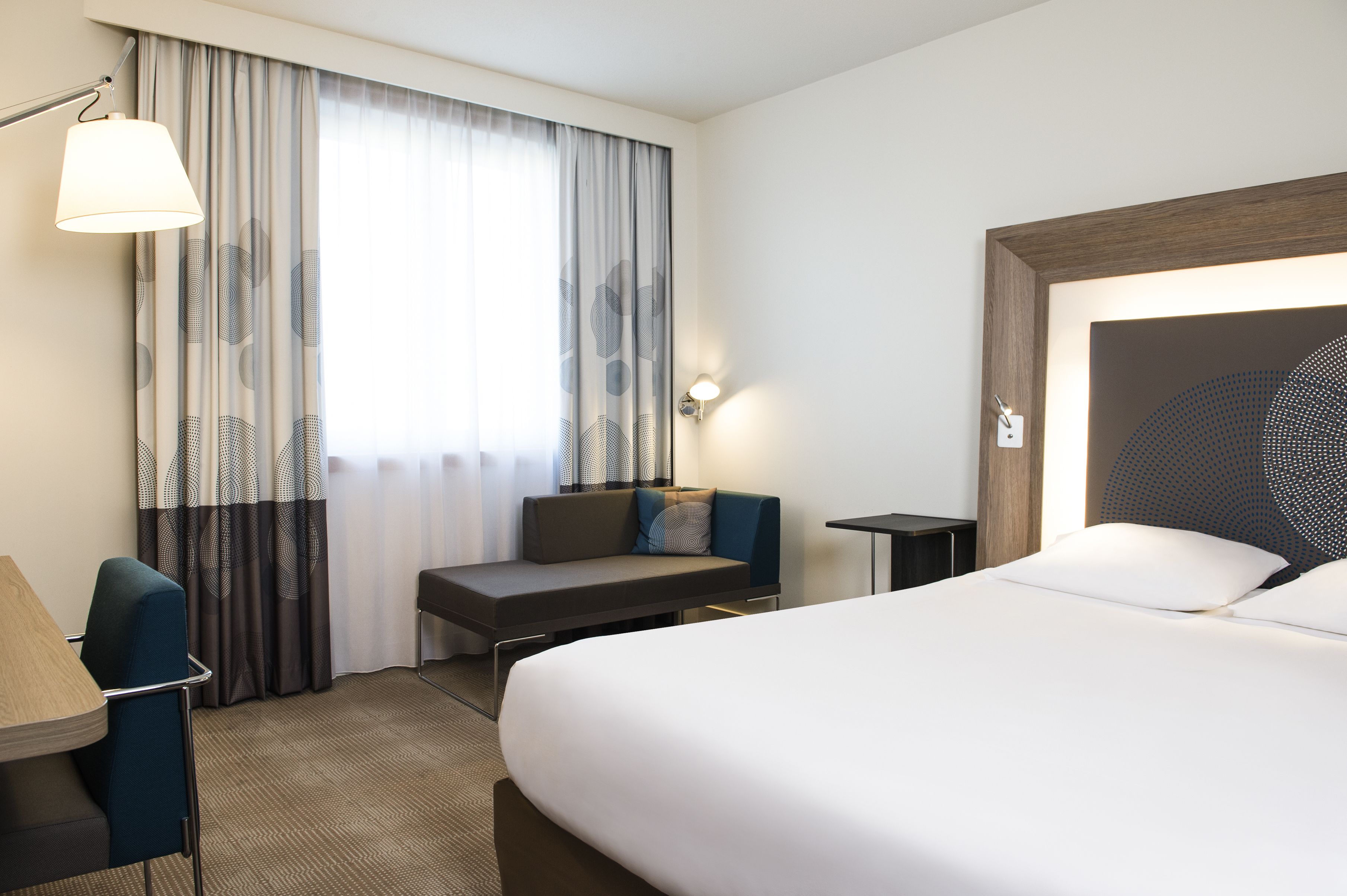 Una habitación de hotel con una cama grande, un escritorio con silla, una mesita pequeña y un sofá.