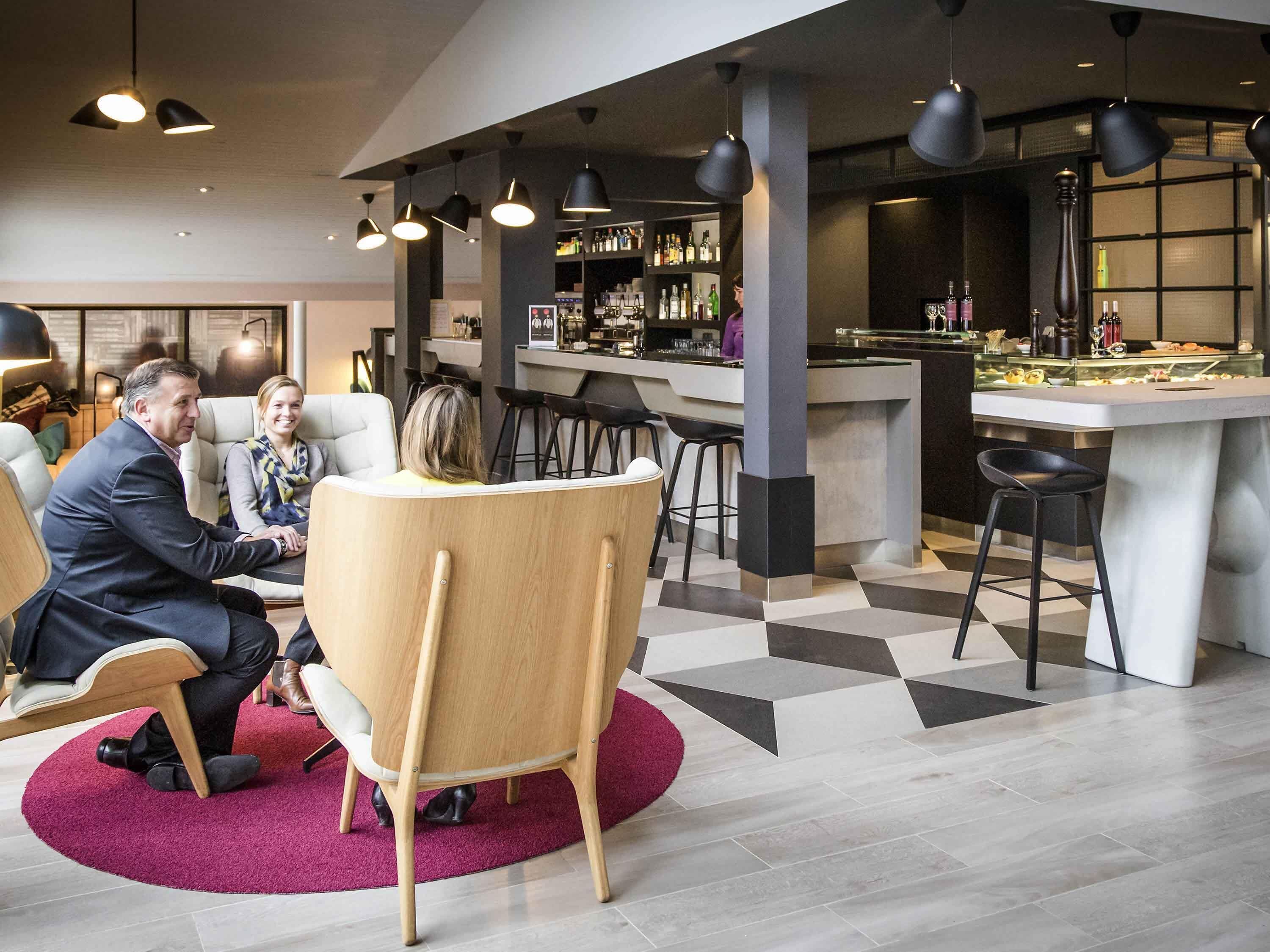 A modern bar area with a bar counter, stools, and a seating area with a round table and chairs.