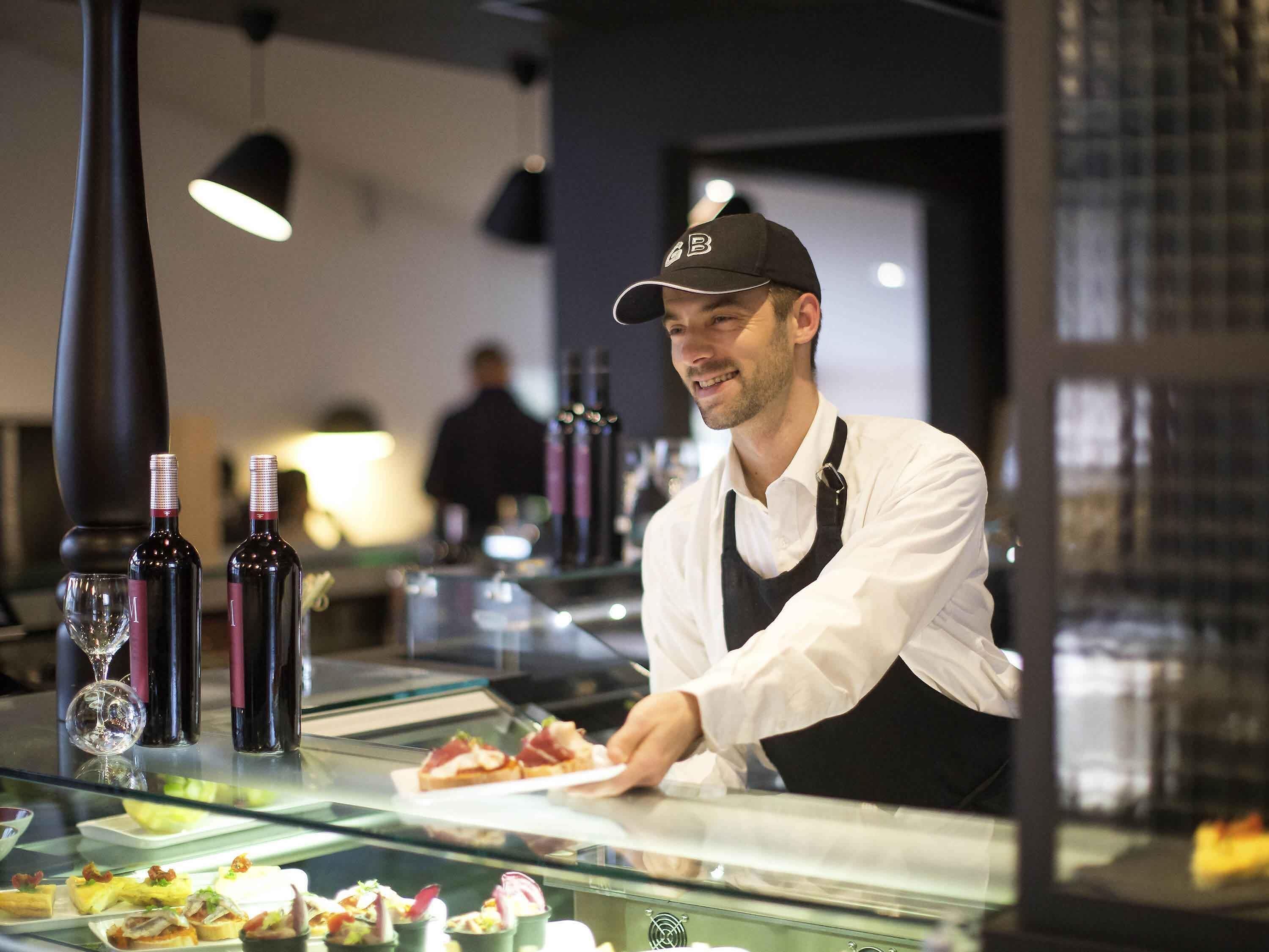 Een restaurantinterieur met een toonbank waarop eten en wijnflessen staan.