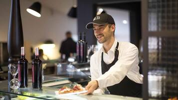 Een restaurantinterieur met een toonbank waarop eten en wijnflessen staan.