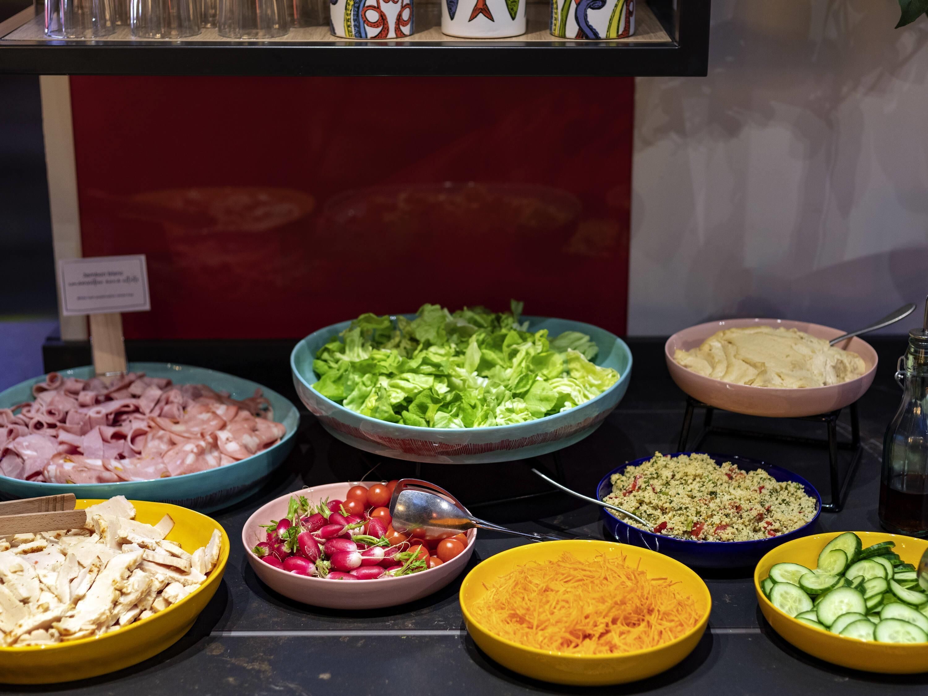 Un bufé con diversos alimentos, incluyendo carnes, verduras y ensaladas.