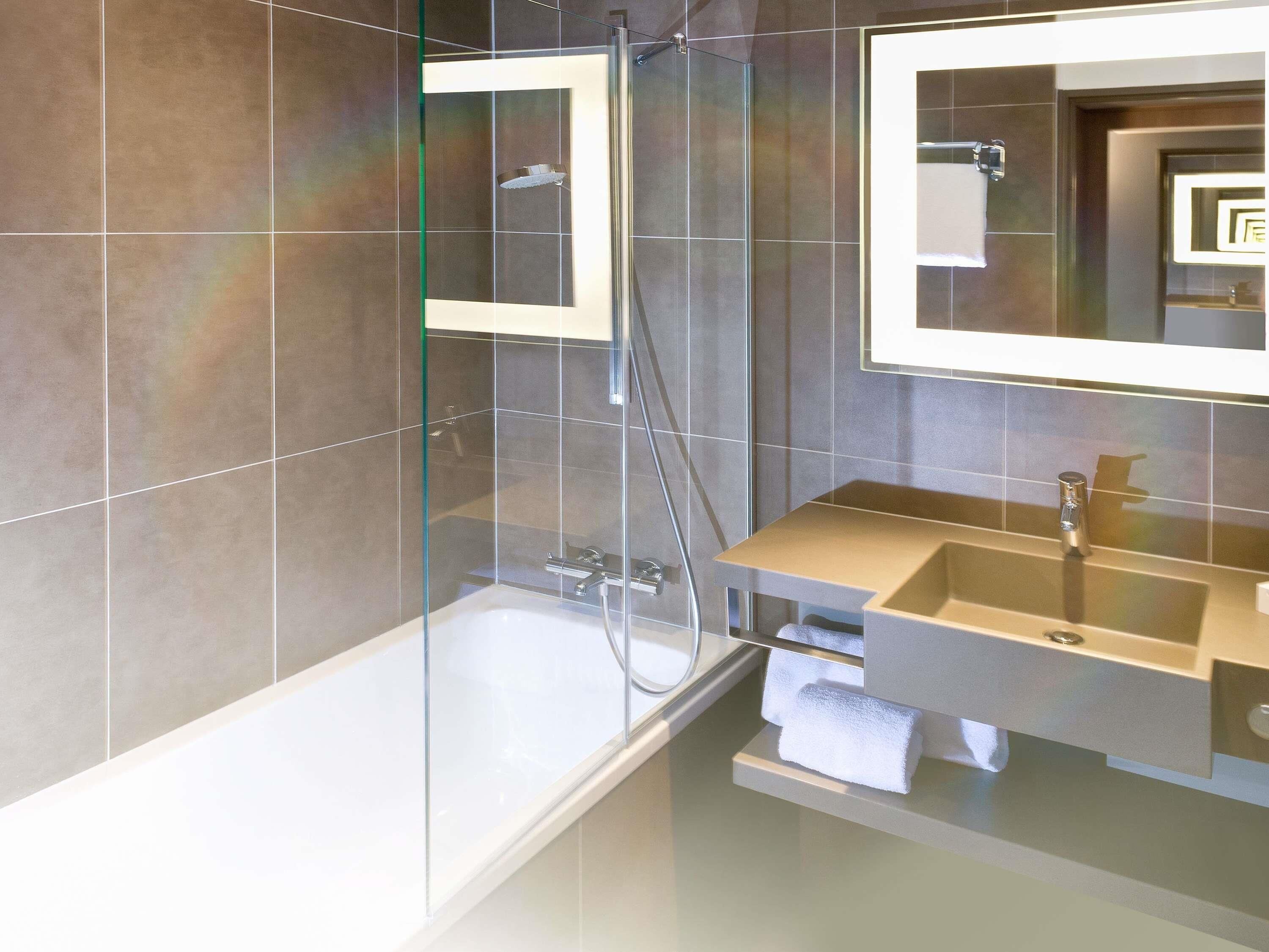 A modern bathroom with a glass-enclosed shower, a vanity with a sink, and a mirror.