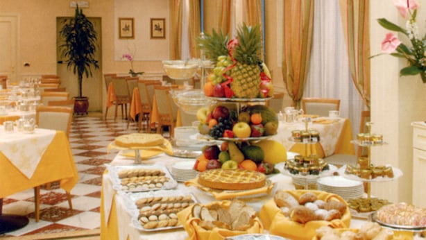 A dining area with a buffet setup featuring various food items and a fruit display. - Andreola Central Hotel (Milan)