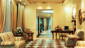 A spacious living room with a checkered floor, striped sofas, and a dining area with a table and chairs. - Andreola Central Hotel (Milan)