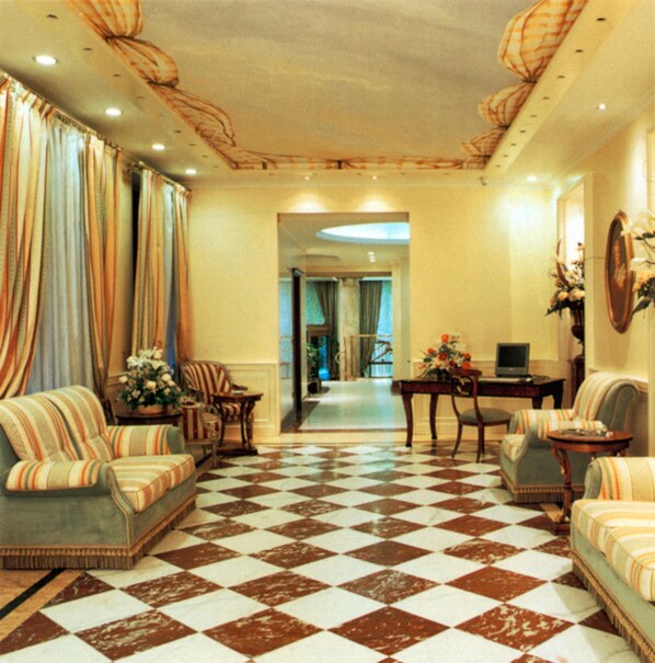 A spacious living room with a checkered floor, striped sofas, and a dining area with a table and chairs.
