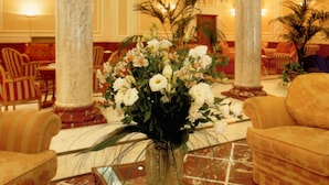 A lobby with marble columns, a floral centerpiece, and a seating area with striped chairs. - Andreola Central Hotel (Milan)
