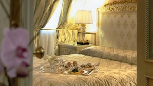 A luxurious bedroom with a neatly made bed, a bedside table with a lamp, and a tray of breakfast items. - Andreola Central Hotel (Milan)