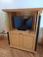 Un mobile in legno con un televisore a schermo piatto, due pensili e uno scaffale.