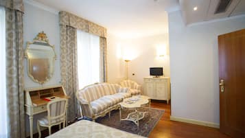 Una habitación de hotel con cama, escritorio, sofá, televisor y armario.