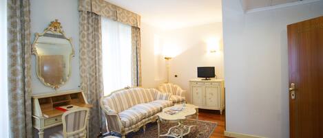 A hotel room with a bed, a desk, a sofa, a television, and a wardrobe.
