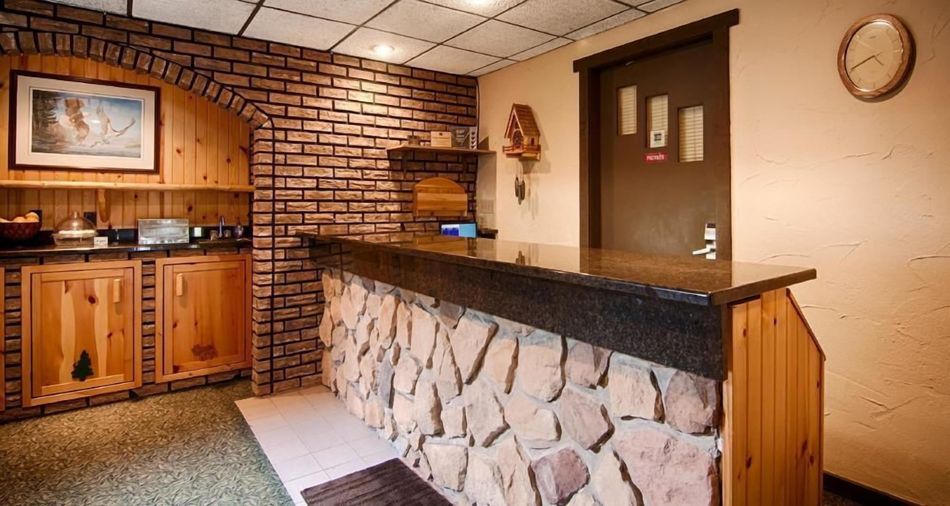 A kitchen with a stone wall, wooden cabinets, and a black countertop.