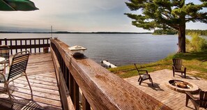 A wooden deck with outdoor furniture and a fire pit overlooking a lake. - Centerstone Resort Lake-Aire (Tomahawk)