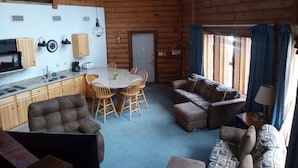 Interior de una cabaña de troncos con cocina, comedor y sala de estar.