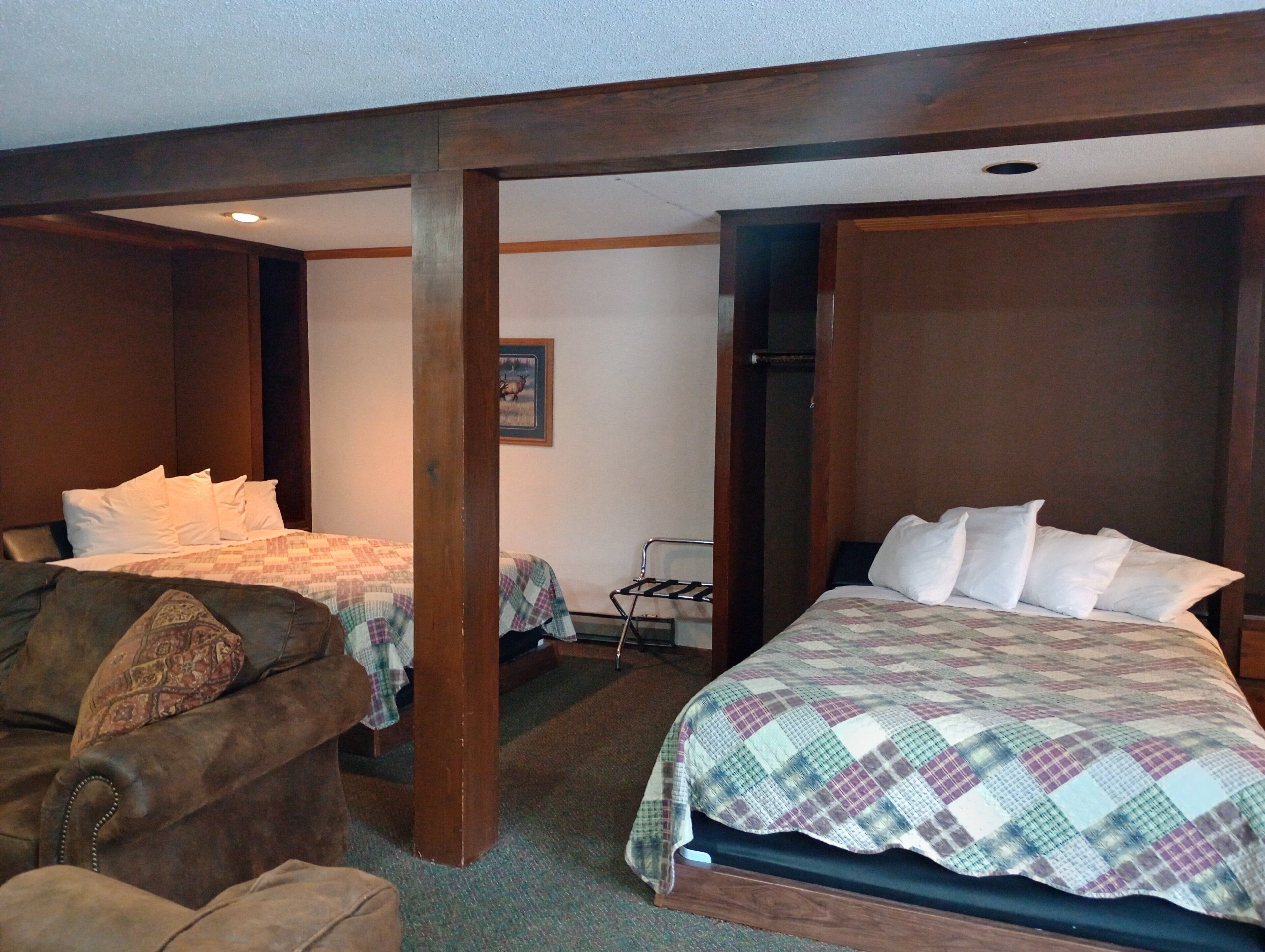 A hotel room with two beds, a wooden ceiling, and a small closet.