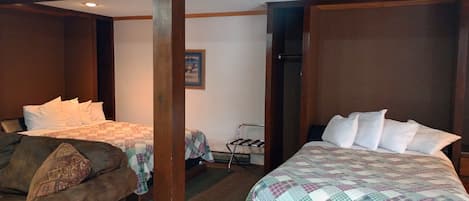A hotel room with two beds, a wooden ceiling, and a small closet.