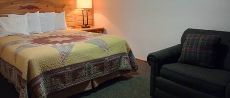 A room with a bed, a nightstand with a lamp, and a dark-colored sofa.