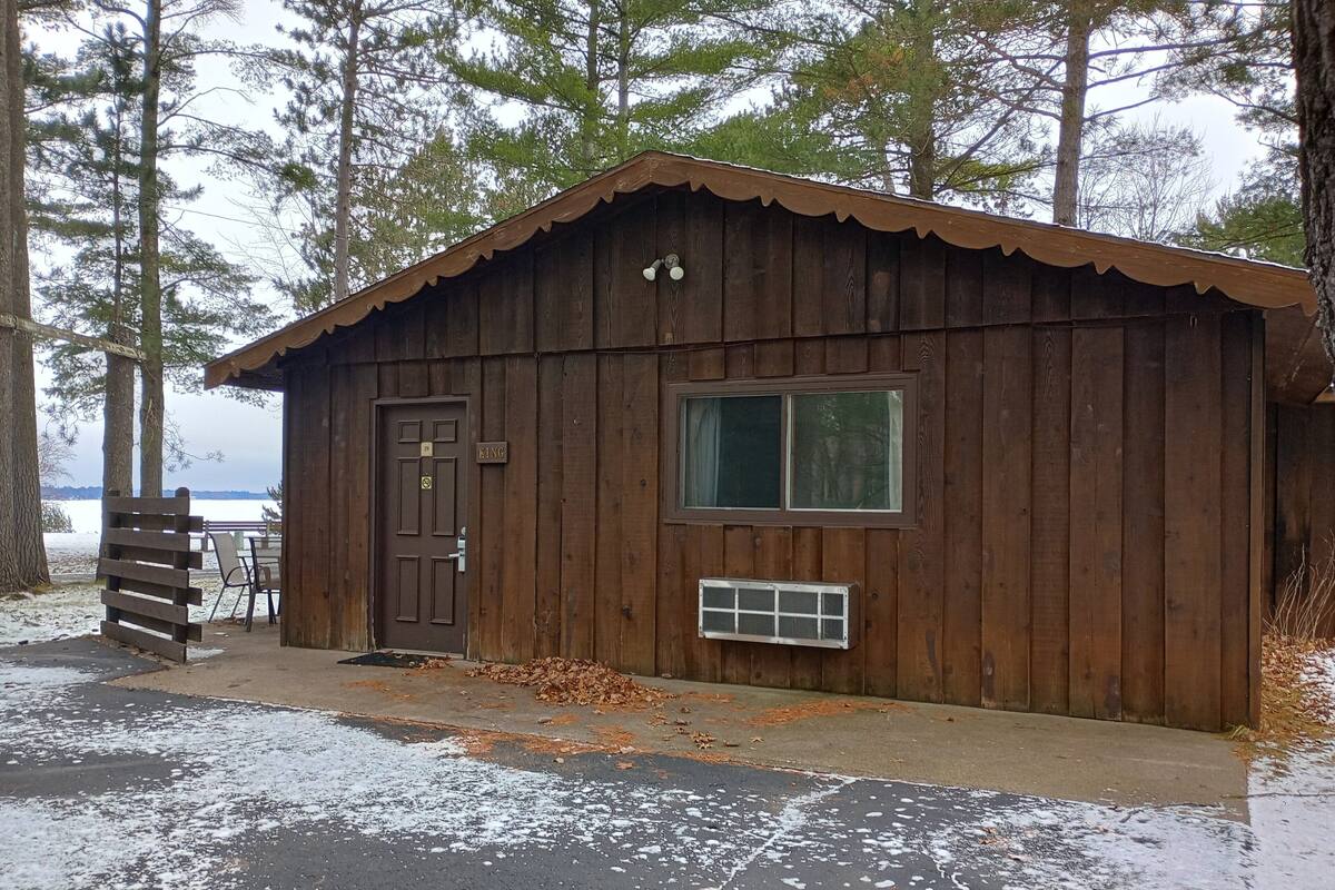 A wooden cabin with a door, a window, and a small vent.
