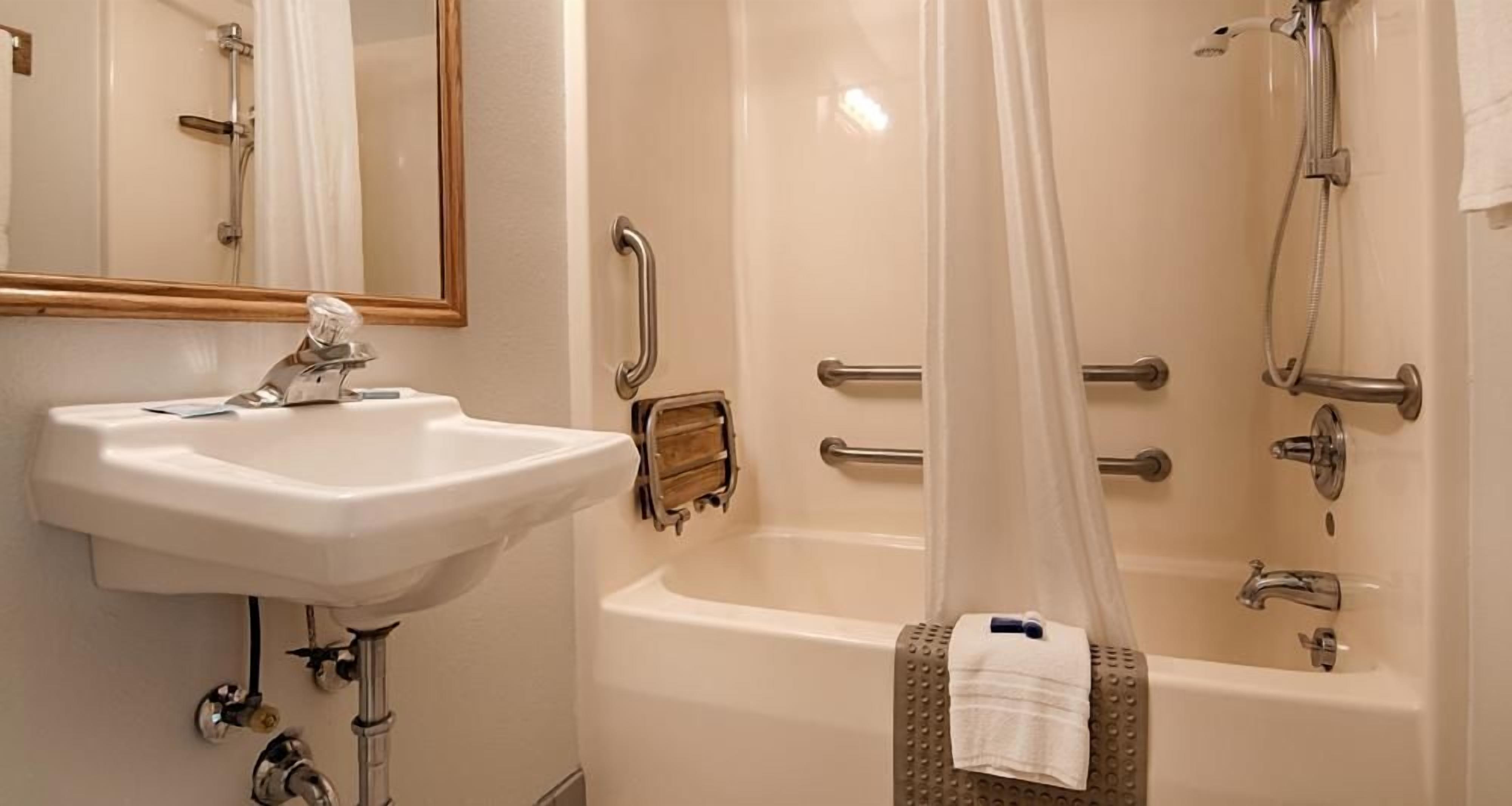 A bathroom with a sink, mirror, shower, and bathtub.