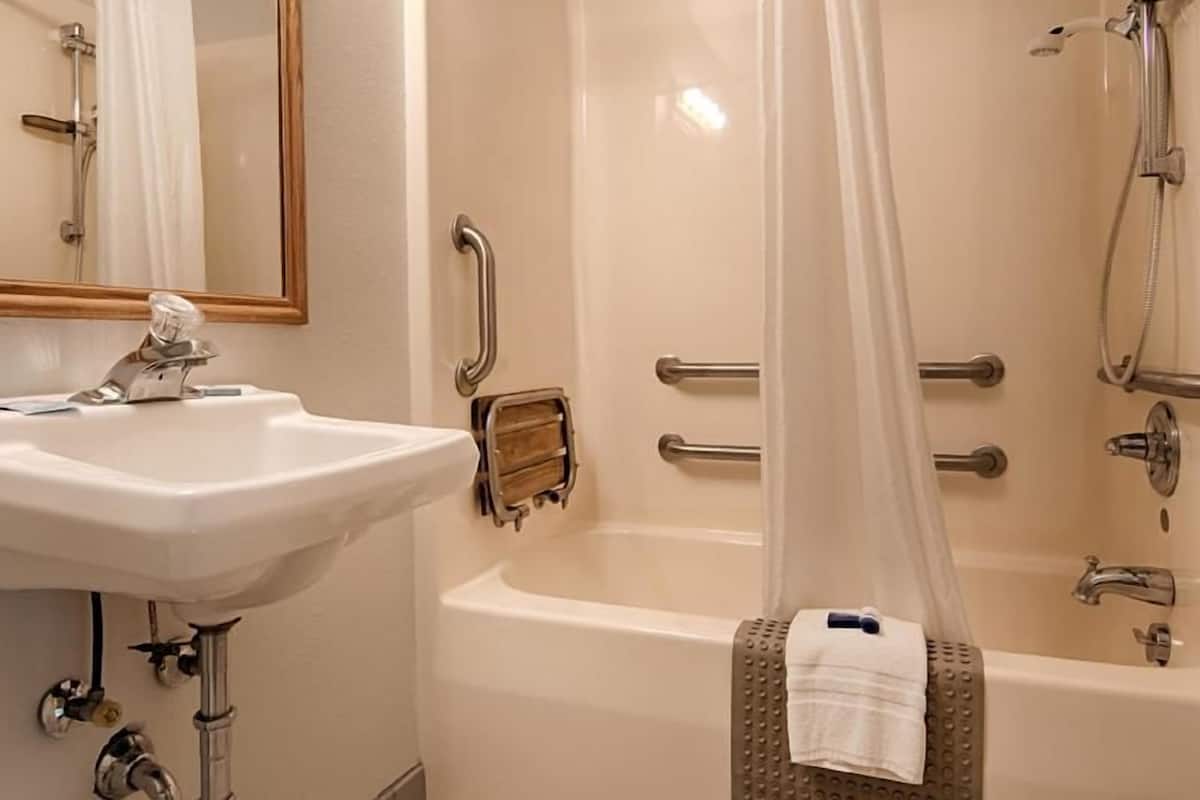 A bathroom with a sink, mirror, shower, and bathtub.