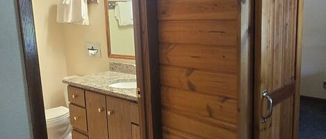 A bathroom with a wooden cabinet, a toilet, and a mirror.