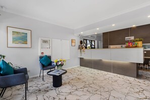 A reception area with a marble floor, two armchairs, a coffee table with flowers, a reception desk, and a framed picture on the wall. - Comfort Inn & Suites Sombrero (Prospect)