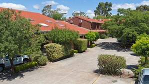 A residential area with multiple houses, a paved driveway, and well-maintained greenery.