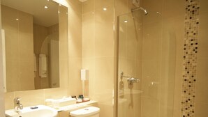 Un baño moderno con cabina de ducha de vidrio, tocador doble y retrete.
