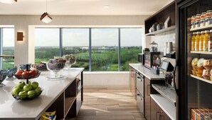 A modern kitchen with a large island, a refrigerator stocked with beverages, and a view of the countryside. -  Delta Hotel Philadelphia Airport (Philadelphia)
