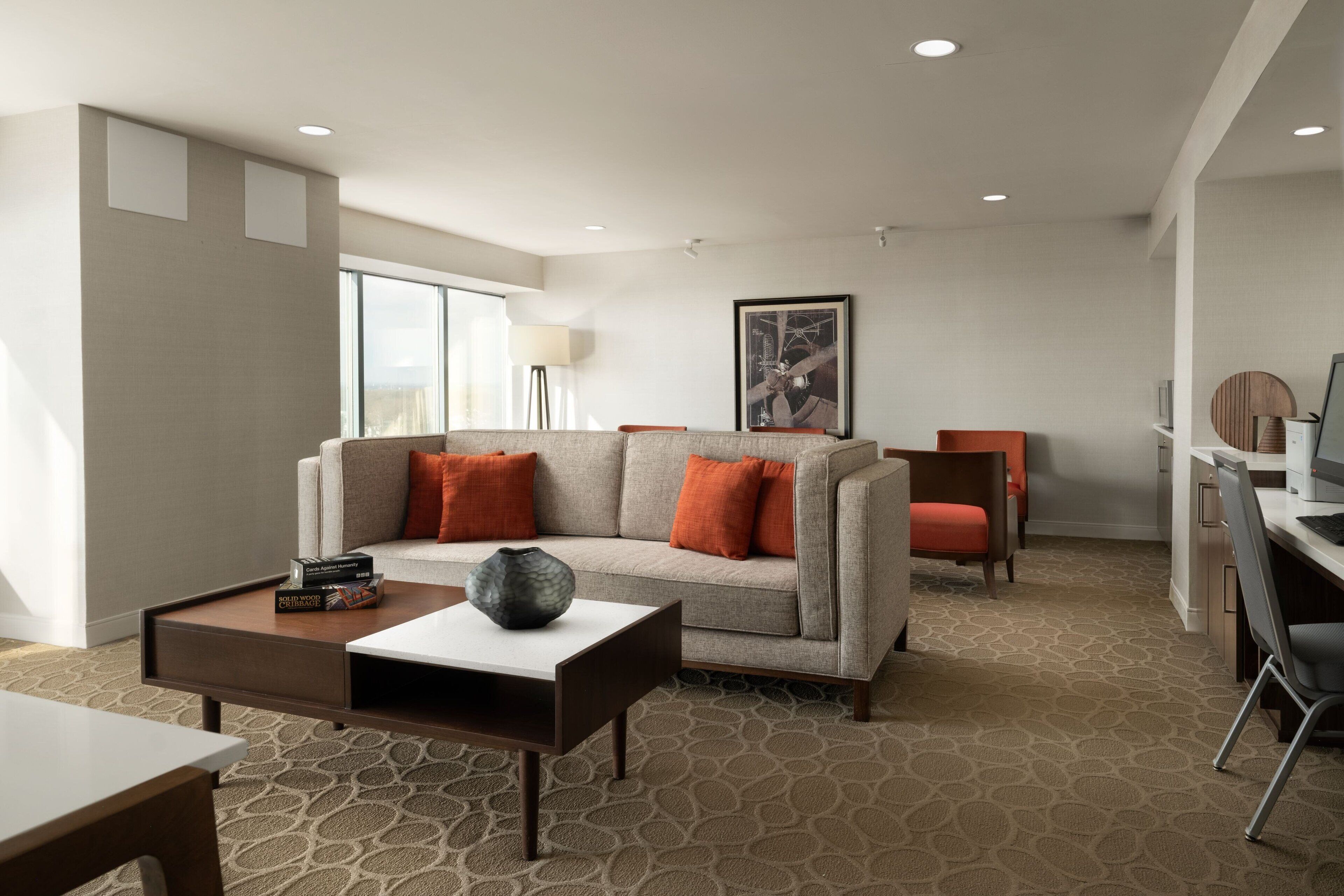 A modern hotel room with a sofa, coffee table, and a desk area.