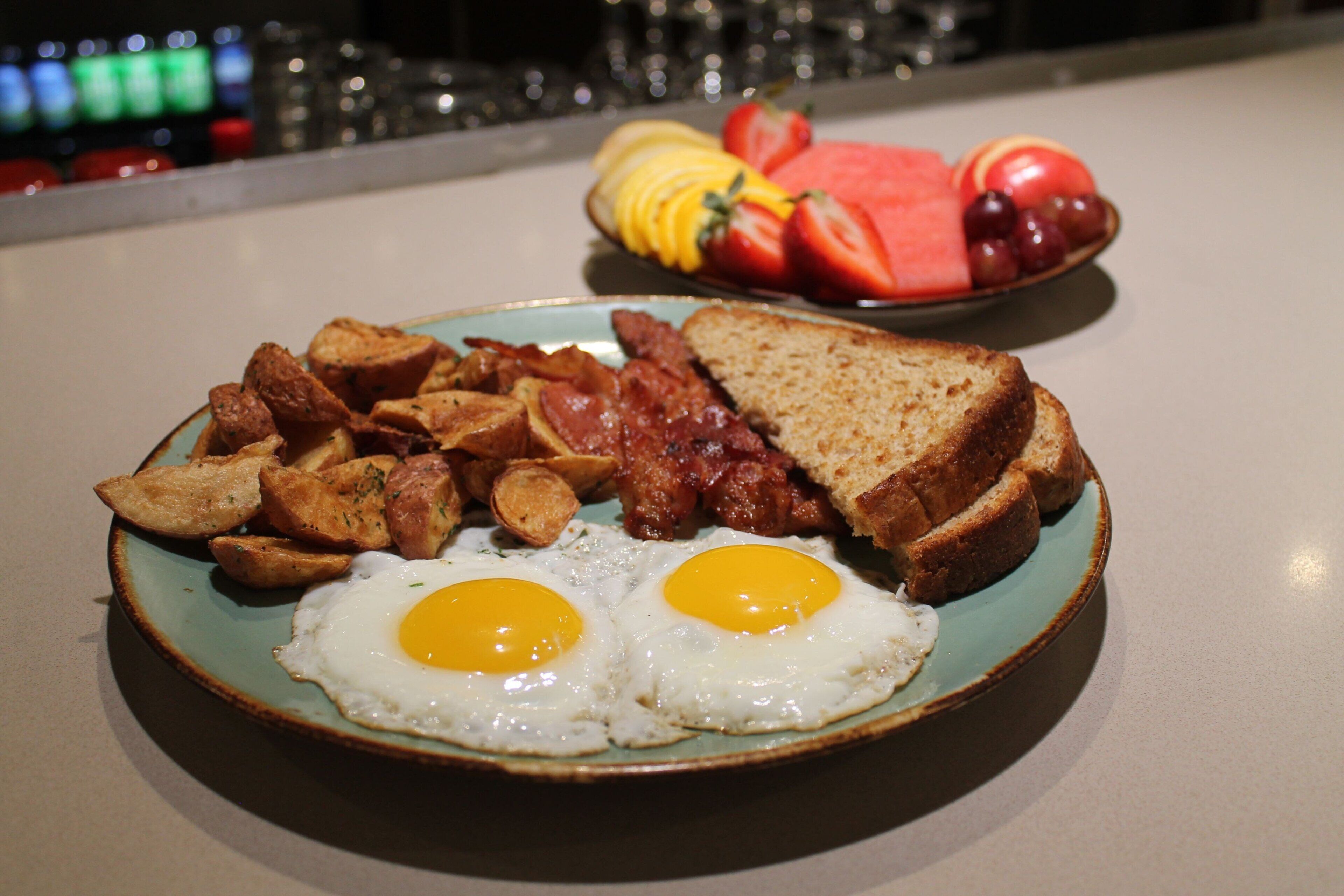 A plate of breakfast food including eggs, toast, potatoes, and bacon.