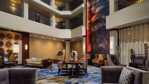 A spacious lobby with a high ceiling, multiple balconies, a large abstract mural, and a central seating area with a round table and chairs. -  Delta Hotel Philadelphia Airport (Philadelphia)