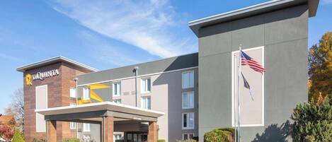 A La Quinta hotel with a modern facade, a covered entrance, and an American flag.