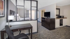 Ein Hotelzimmer mit Schreibtisch, Stuhl, Fernseher und Blick ins Badezimmer.