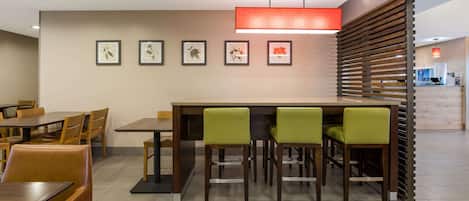 Un comedor moderno con una mesa larga y sillas, una obra de arte enmarcada en la pared, y un separador de madera con listones.