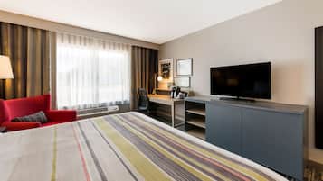 Une chambre d’hôtel avec un grand lit, un bureau avec une chaise, une télévision et une armoire.