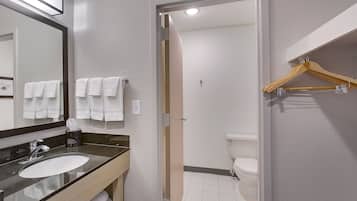 A bathroom with a sink, mirror, and two white towels hanging on the wall.