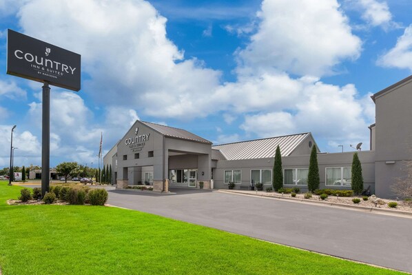 A Country Inn & Suites building with a modern design, featuring a large sign, a covered entrance, and a well-maintained lawn.