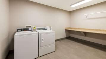 A laundry room with two front-loading washing machines, a microwave, and a countertop.