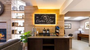 Un espace bar où l’on sert du café, avec un panneau indicateur, des machines à café et un coin salon doté d’une cheminée.