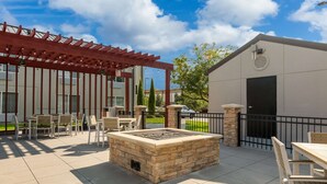 Un espace extérieur aménagé avec une terrasse, un foyer, des sièges et une pergola.