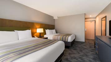 Une chambre d’hôtel avec deux lits, un bureau et un miroir.