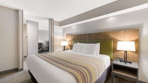Une chambre d’hôtel avec un grand lit, deux tables de chevet avec des lampes, une tête de lit en bois et un sol recouvert de moquette.
