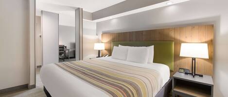 A hotel room with a large bed, two bedside tables with lamps, a wooden headboard, and a carpeted floor.