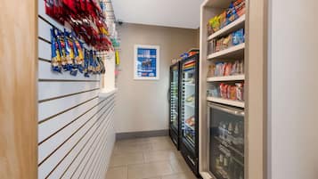 Pasillo estrecho con bolsas de aperitivos a la izquierda y productos refrigerados a la derecha.
