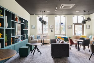 Un espacio de descanso moderno con asientos, una estantería y ventanas amplias.
